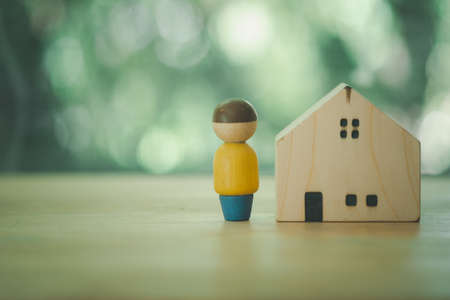 Wooden figures of people and a house on a nature background with copy space on the left. concept of...