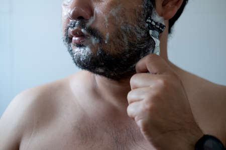 Handsome young man with razor in hand while shaving. Men care concept.の写真素材