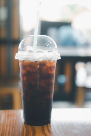 Thai style black coffee in plastic glass on wood tableの写真素材