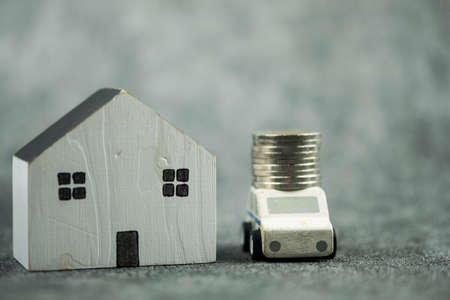 Close up of model home and coin placed on the car. Collect money to buy a new car, home, account, home expense and investment concept.の写真素材