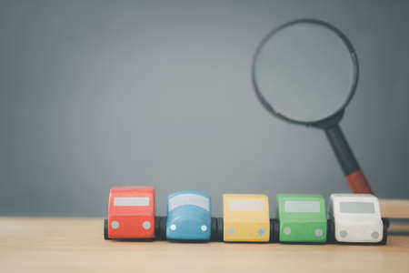 A row of wooden toys with a magnifying glass background. The concept of selection and inspection of a car.の写真素材