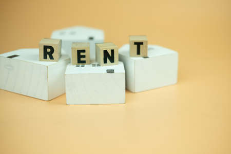 Wood cubes blocks with word RENT placed on wood home. The concept of the cost of housing rentの写真素材