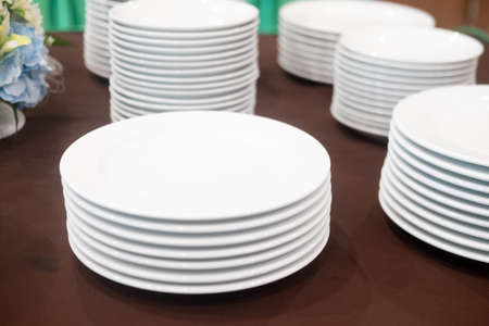Stack of clean white plates in a restaurant for buffetの写真素材