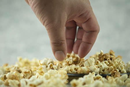 Hand picking a tasty popcorn, close up