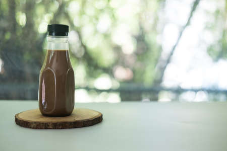 Coffee bottles placed on wooden saucer against nature backgroundの写真素材