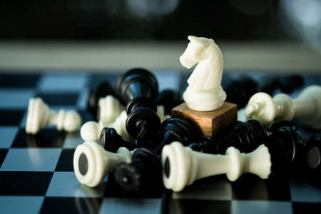 White horse chess standing among fallen pawns. The concept of resilience, perseverance, immunity and...