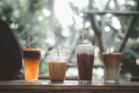 Four iced coffee drinks such as Mocha, black coffee mix orange juice, Latte and cappuccino with paper strawの写真素材