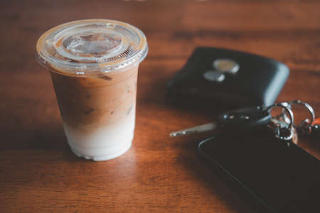 Close view of iced coffee put on the table next to the wallet, car keys and mobile phone in the cafe. Office deskの写真素材