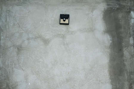 Old solar-powered motion sensor light on cement or concrete wall background, copy spaceの写真素材