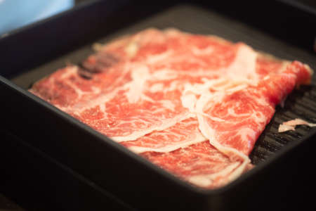 Close up sliced raw wagyu beef in a black tray at japanese shabu restaurantの写真素材