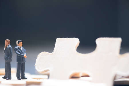 Miniature businessman standing in the wood jigsaw puzzle piece. Business strategy conceptual photo
