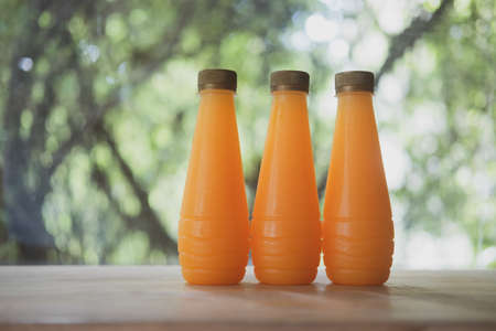 Orange juice in plastic bottles with gold lid on wood tableの写真素材