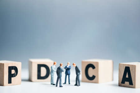 Miniature businessman meeting for analysis PDCA. The concept of plan do check act. Alphabet letter with word PDCA abbreviation of plan do check act.の写真素材