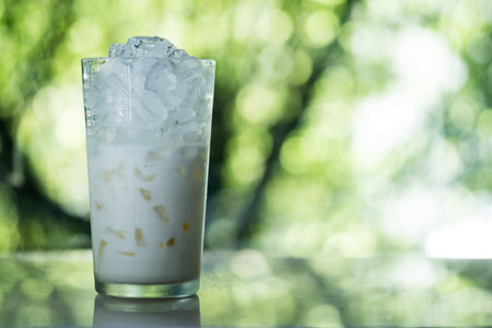 Fresh milk with ice in glass against nature backgroundの写真素材