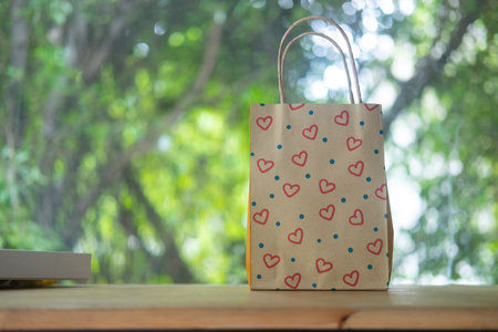 Small brown paper bags with handles and pattern of red hearts on wood tableの写真素材