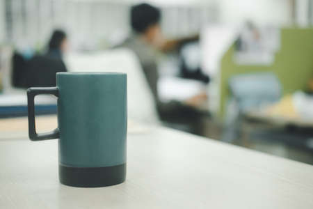 Green mug on table and blur office modern room background. Blank drink cup for your design.の写真素材