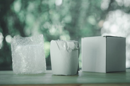 Protecting glass containers in wrap and glass containers in paper for put in white paper box for transportの写真素材