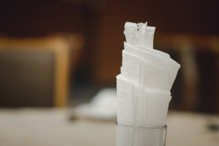 White paper napkin is placed in a glass on the table in the banquet room. Selective focusの写真素材