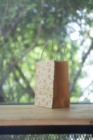 Brown paper shopping bag and heart shape on wood tableの写真素材