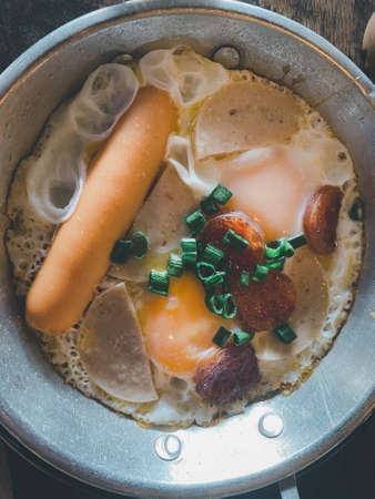 The breakfast Thai food Panned eggs is fried egg topping with sausage, vegetable and bacon in the hot pan.の写真素材