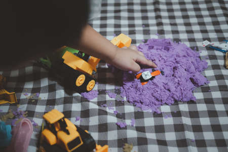 Cropped view of man cute Asian young boy playing with sand alone at home with sand toys and toy construction machinery at home during coronavirus outbreak. Creative play for kids conceptの写真素材