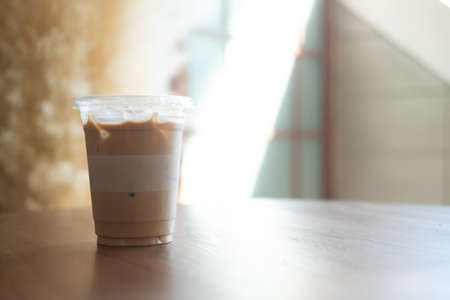 Iced latte in plastic glass on wood table with light morning, a plastic glass 16ozの写真素材