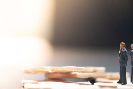 Miniature businessman standing and thinking at the missing wood jigsaw puzzle piece. Business problem to be success conceptの写真素材