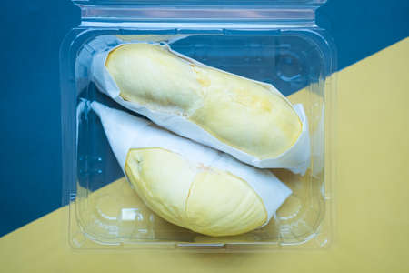 Fresh durian in the clear plastic box on black and yellow backgroundの写真素材