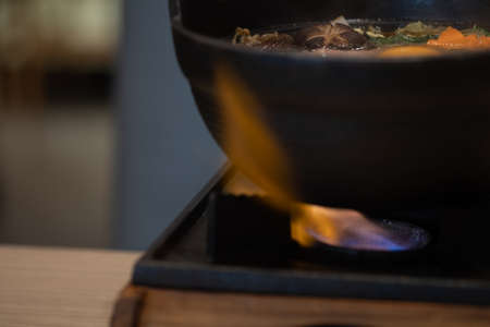Close up of traditional vintage Japanese suki pot. Fresh pork dip into hot Japanese suki soup with vegetablesの写真素材