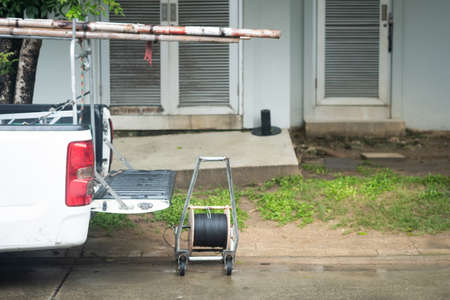 White pickup car with opened truck and wooden ladder and roll wires for repair wires