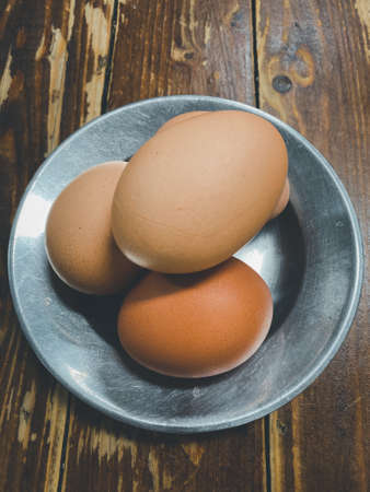 A group of raw egg in aluminum dish on wood tableの写真素材