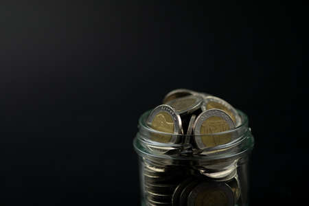 Full of Thai ten baht coins in glass on a black backgroundの写真素材