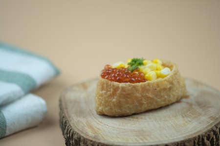 Tofu skin sushi topped with salmon roe and corn. Close upの写真素材