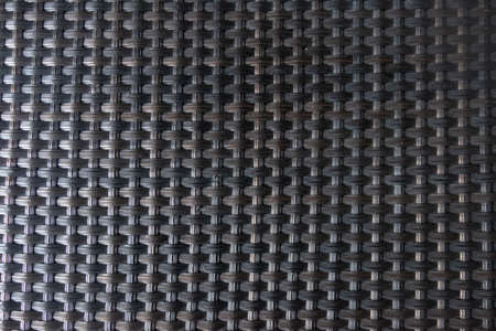 Background Black wicker plastic table mat. Outdoor furniture and abstract background conceptの写真素材