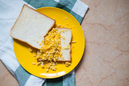 Scrambled eggs with toasted bread on yellow dishの写真素材