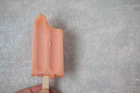 Cropped Image of person holding bitten pink ice cream