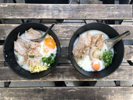 Top view two bowl of congee with pork, entrails and egg, it rice has softer texture for breakfast in the morningの写真素材