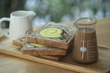 An easy set of breakfast include bread hot coffee and fresh milk on wood tray