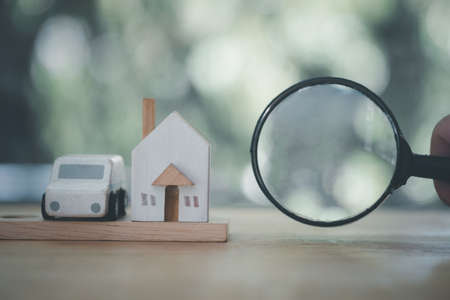 Magnifying glass with a toy house and a car suggesting family investmentsの写真素材