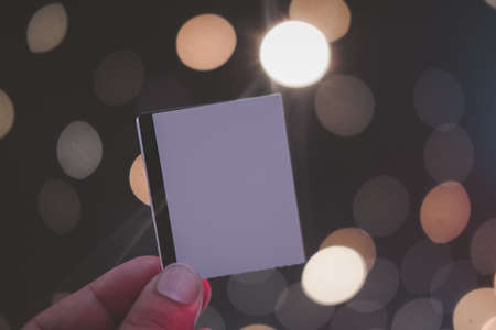 Male hand holding blank sheets of paper (tickets, flyers, invitations, coupons) on bokeh light...
