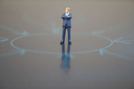 Businessman miniature standing on center of circle with multiple arrows point to center of circle. Business and direction conceptの写真素材