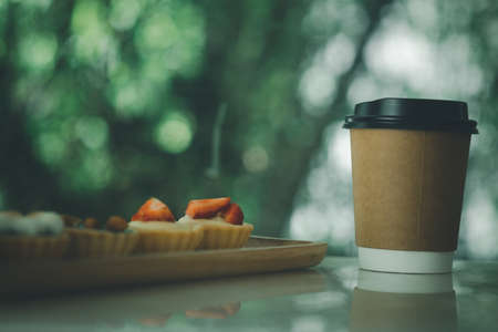 A paper cups with a lid for hot tea or hot coffee to go with sweet mini tart cake