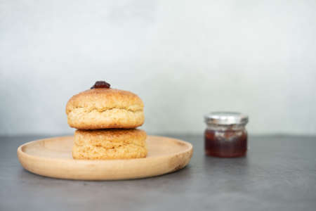 Photo of delicious homemade butter scones on wood dish with strawberry jam and clotted creamの写真素材