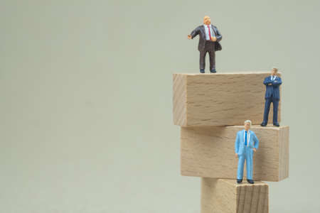 Miniature businessman thinking and standing on step wooden blocks thinking for success business...