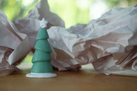 Ceramic Christmas little tree on crumpled paper background. Festive is a coming concept.