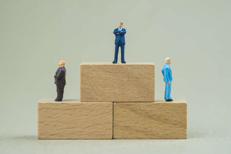 Miniature people : Businessman standing on top of brick and two businessmen standing right and left...
