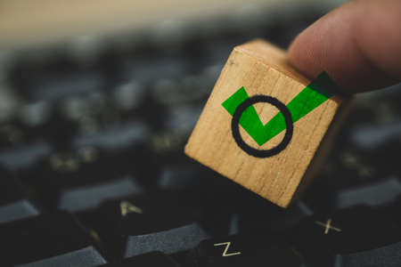 Hand touching wood block with ticking checkbox out of empty boxes. Business technology concept. The concept of choice and making the right decision. Business managementの写真素材