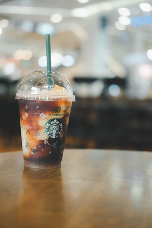 Bangkok, Thailand - November 15, 2021 : Yuzu Cold Brew in a reusable cup with a special 50th anniversary design on wood tableのeditorial素材