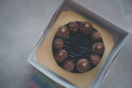 A straight close up shot of a whole chocolate cake with topping in boxの写真素材