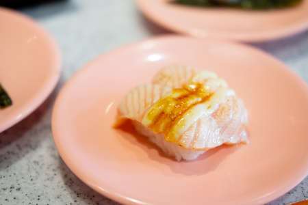 Grilled salmon sushi topped with sweet sauce on pink dish, Japanese food.の写真素材